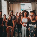 Grupo diverso de jovens participa de uma reunião comunitária em um estúdio amplo e criativo.