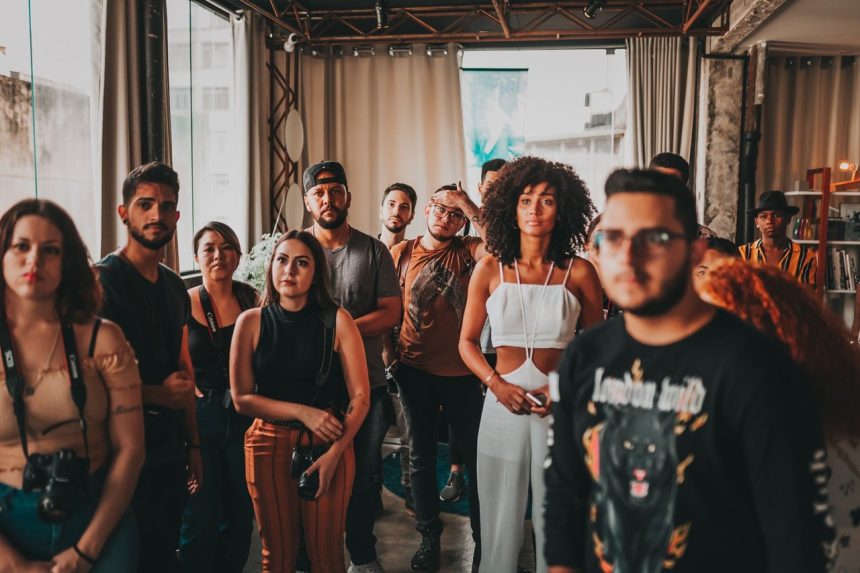 Grupo diverso de jovens participa de uma reunião comunitária em um estúdio amplo e criativo.