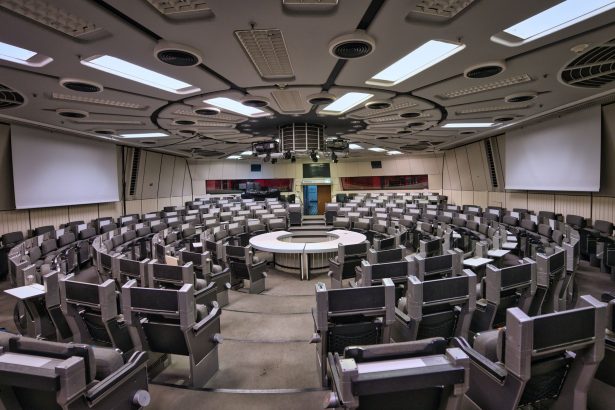 Sala de conferências futurista, vazia, com assentos circulares e elementos de design de alta tecnologia.