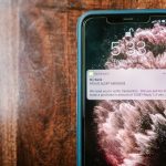 Smartphone exibindo uma notificação de alerta de fraude sobre uma superfície de madeira
