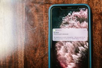 Smartphone exibindo uma notificação de alerta de fraude sobre uma superfície de madeira